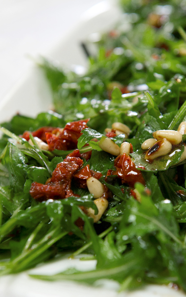 Roquette, juliennes de tomates séchées au soleil et noix de pin grillées